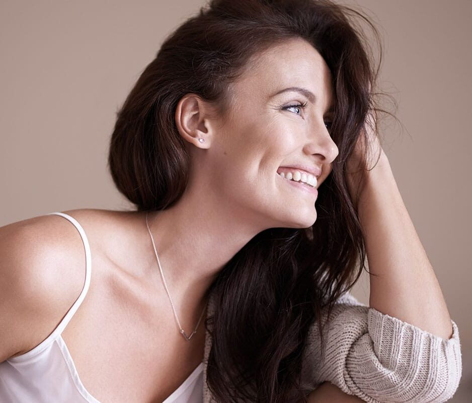 A brunette woman smiling looking to the side.
