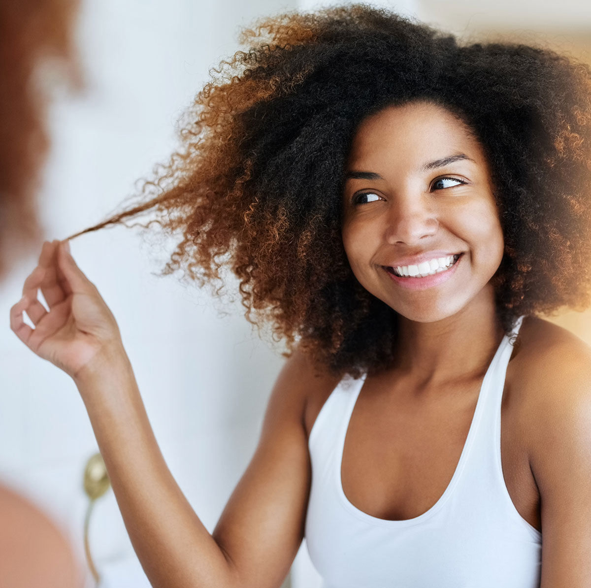 A woman with curls admiring her hair.