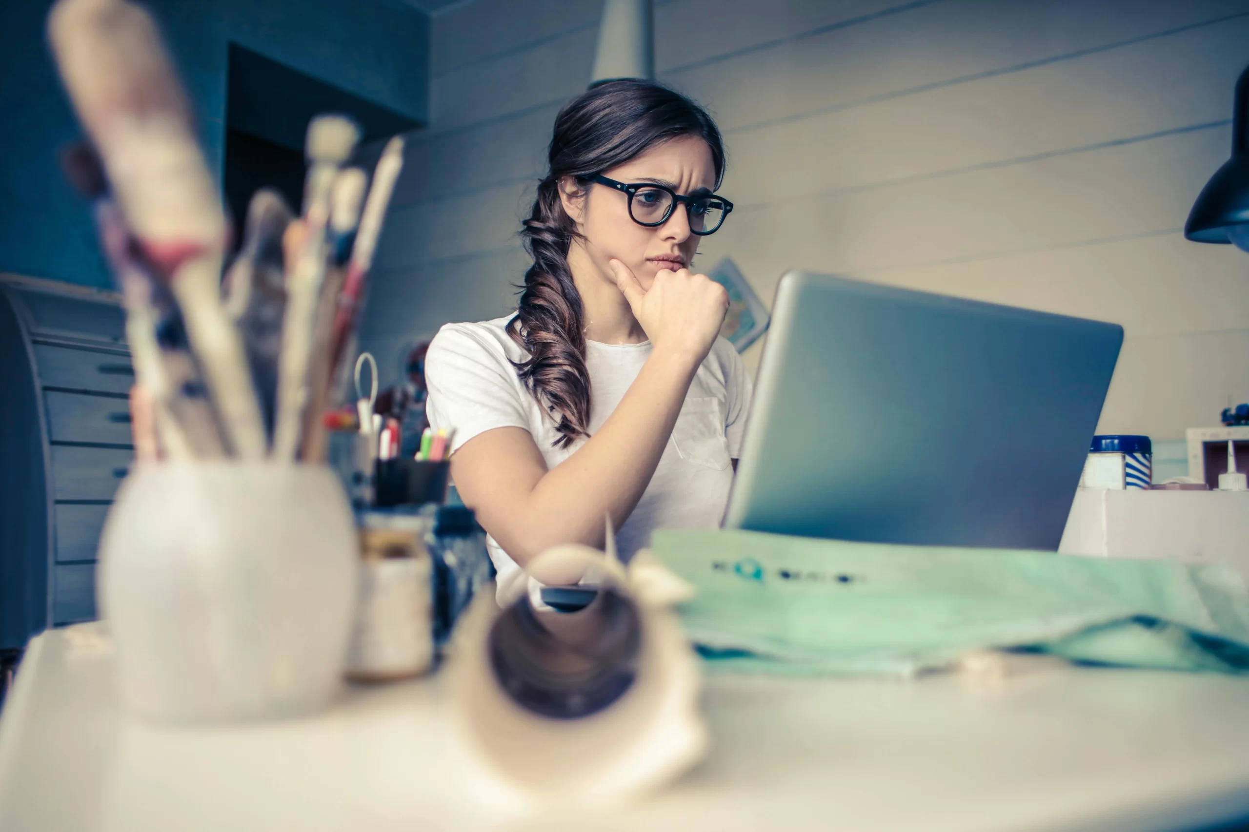 A woman sitting at a desk researching on her laptop.