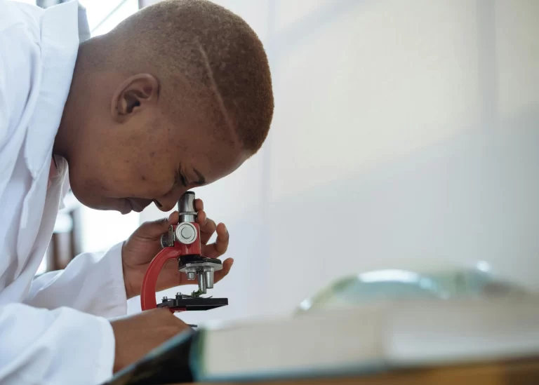 A health professional looking through a small microscope.
