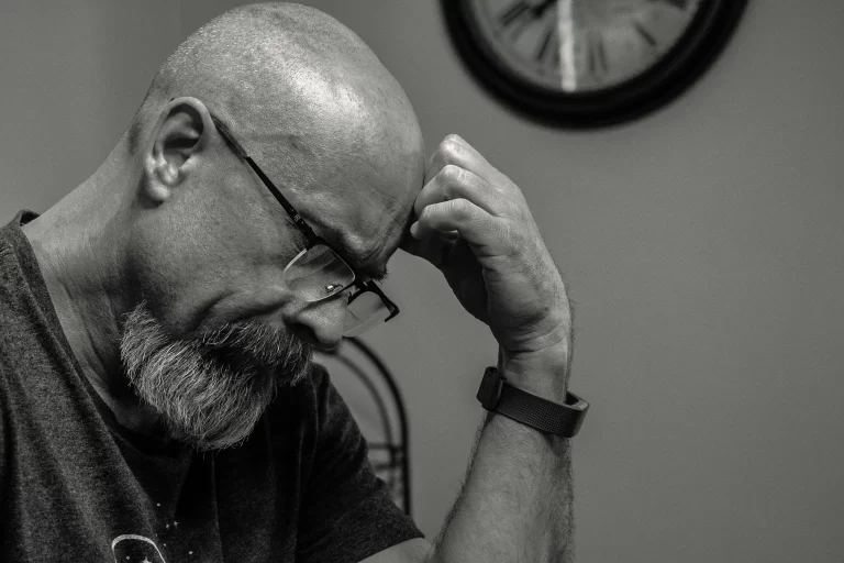 A man with a bald head and a beard contemplating.