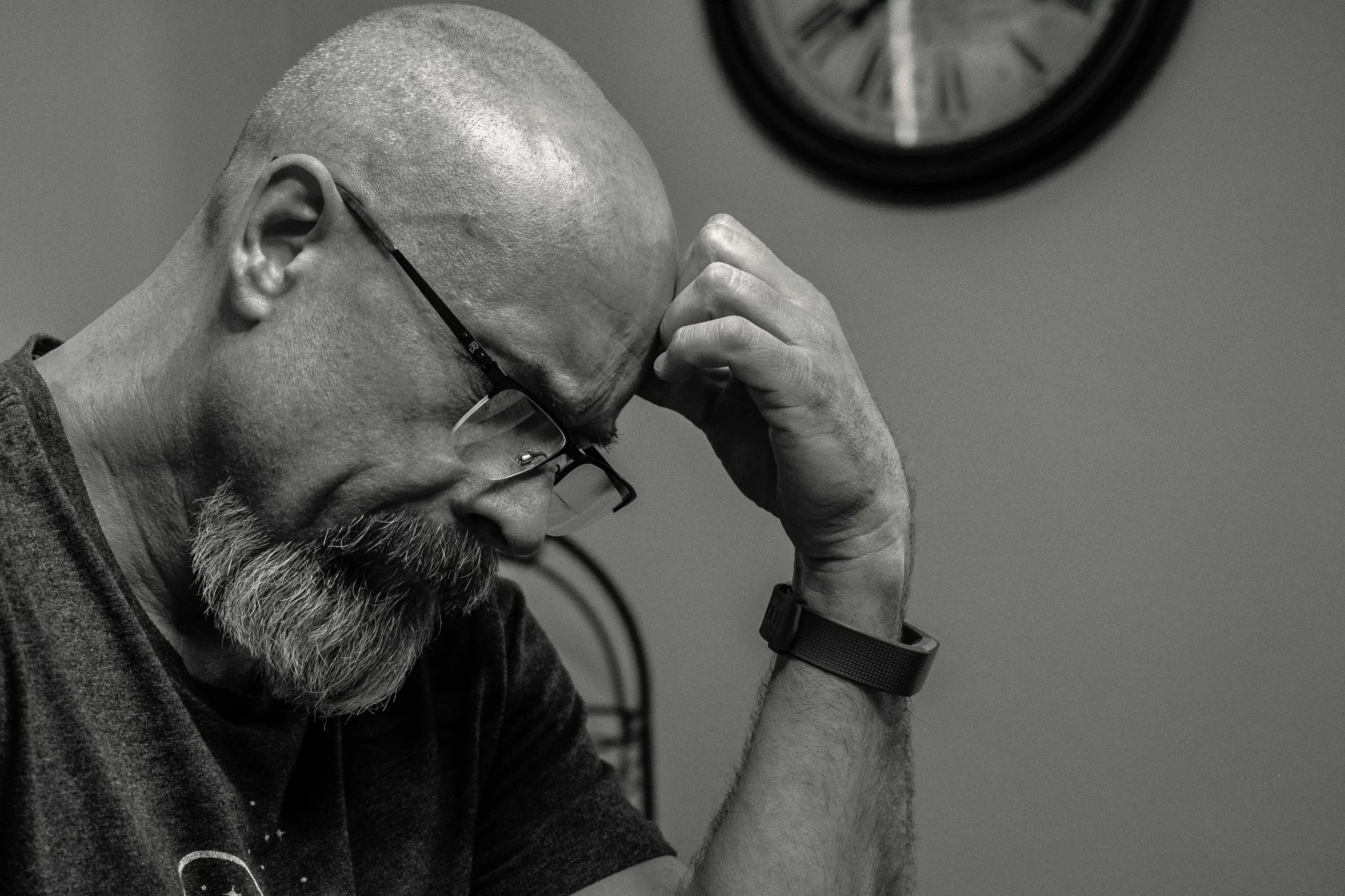 A man with a bald head and a beard contemplating.