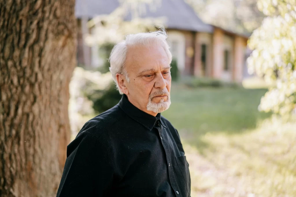 A man with thinning hair standing outside.
