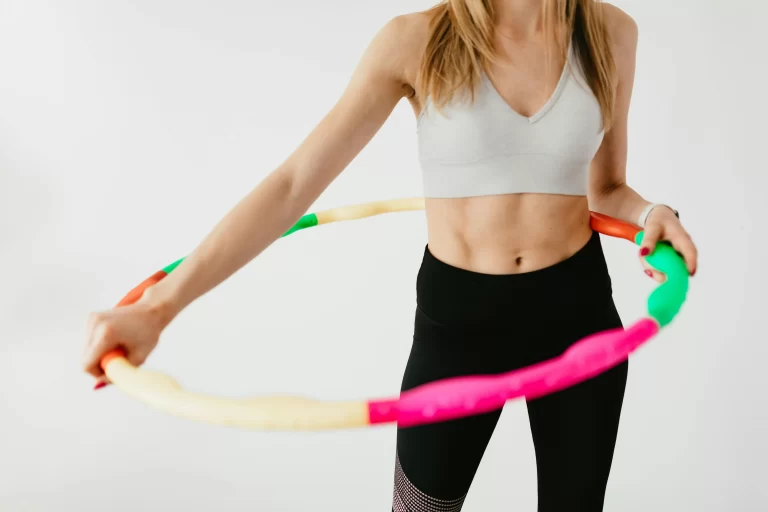 A fit woman with a hula hoop around her waist.