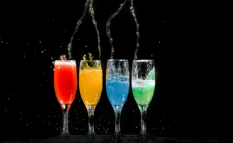 4 glasses of different colored drinks being poured from above.