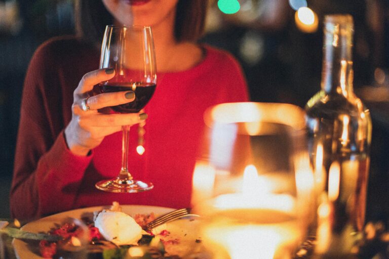 A woman sitting with a glass of red wine.