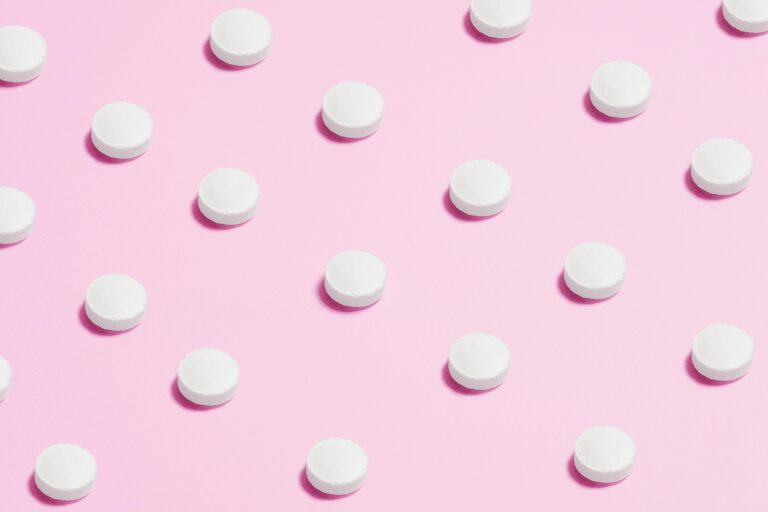 Picture of pills lined up on pink background