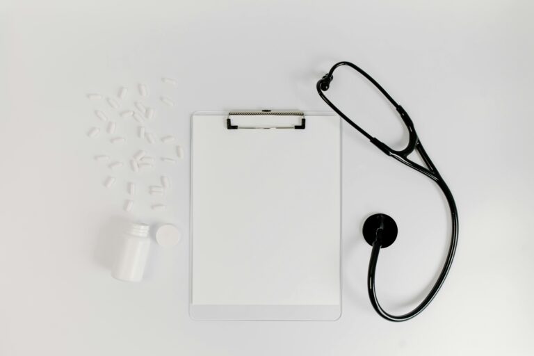 A bottle of spilled pills next to a clipboard and a stethoscope