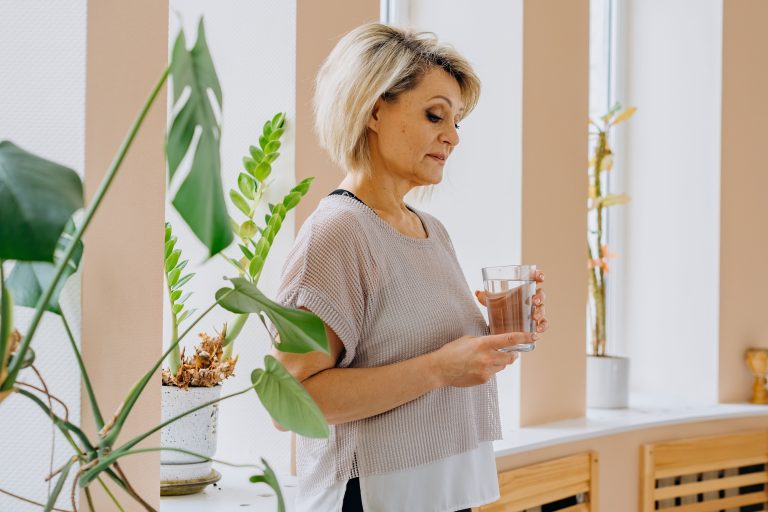 Woman holding a cup of water looking like their in thought.